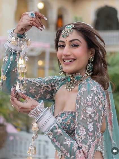 A happy bride radiates joy in our exclusive designer pastel lehenga. The unique blouse design and delicate floral embroidery make this a standout piece, perfect for making memories.