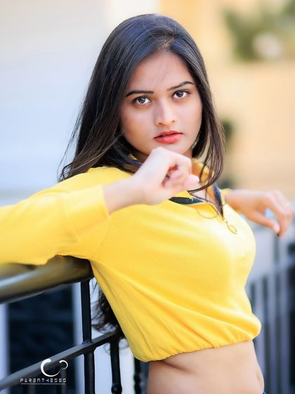 A powerful and confident pose, leaning on a railing. Her direct gaze is strong and captivating.