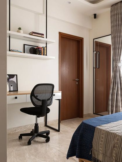 This guest room includes a floating study desk and suspended open shelves, providing a workspace and storage without taking up any floor area.