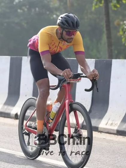 A rider in a powerful, aerodynamic tuck, pushing hard on his high-performance race bike.