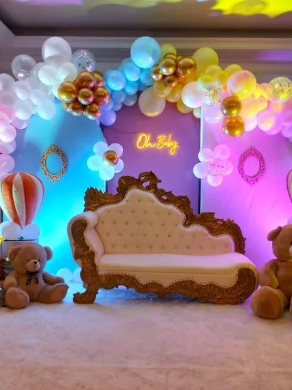 A classic baby shower setup with a "Boy or Girl" theme. The decor includes pink and blue balloons, teddy bears, and an ornate sofa for the parents-to-be.