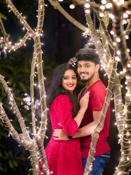 A happy couple poses among the fairy-lit trees, a simple yet beautiful way to capture their joy.