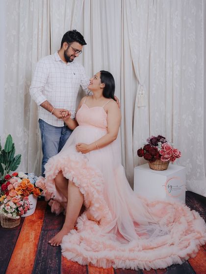 A sweet and gentle pose, with the couple holding hands and sharing a look. The floral props add to the soft, romantic feel of the scene.