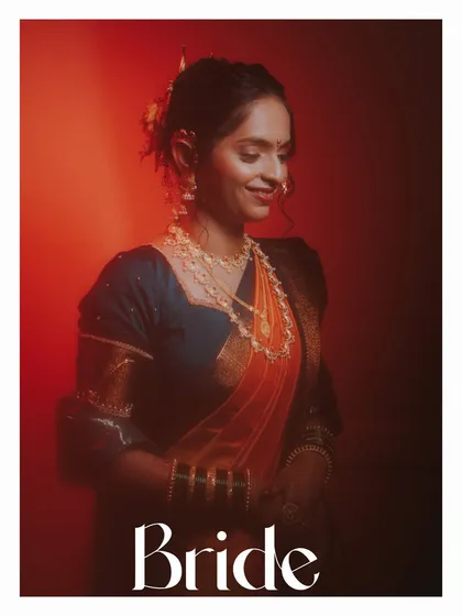 A stunning portrait of a Maharashtrian bride. The dramatic red lighting highlights the rich colors of her Navvari saree and traditional gold jewelry, creating a powerful and artistic image.
