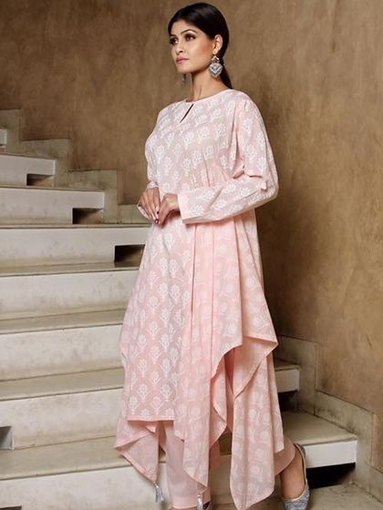 A model posing on a staircase in a pink asymmetrical kurta, showcasing unique silhouettes in ethnic fashion.
