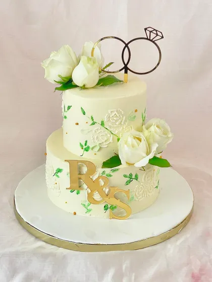 A beautiful two-tiered engagement cake to celebrate the beginning of a new chapter. It features delicate hand-stenciled details, fresh white roses, and a custom monogram.