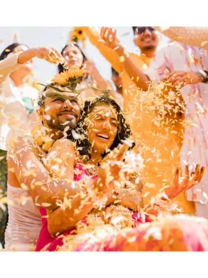 A shower of love and petals for the happy couple. This action shot, full of movement and joy, perfectly captures the high energy and celebratory spirit of their sunflower-themed Haldi.