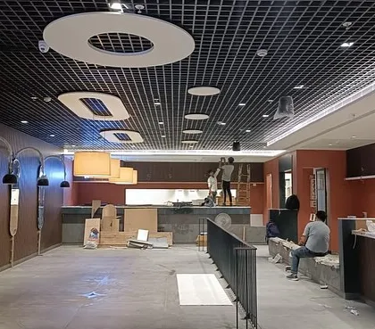 This work-in-progress photo shows the Haldiram's Pitampura site during construction. The grid ceiling and the framework for the arched wall mirrors are in place, showing the skeleton of the design taking shape.