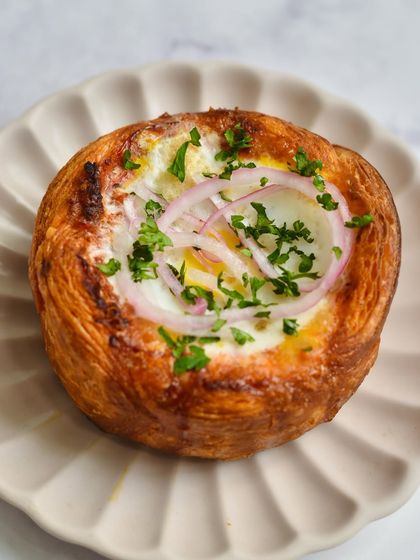 Our Patatas Bravas Puff Galette, a savory creation from our Spanish pop-up. It features a perfectly baked egg nestled in a flaky puff pastry crust.
