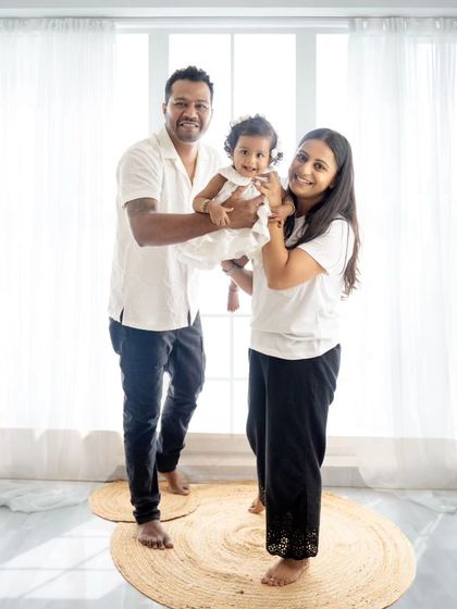 A happy family of three, smiling brightly for the camera. The coordinated white outfits look fresh and timeless.