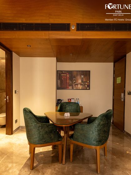The suite includes a dedicated dining nook with plush green velvet chairs. It's a perfect spot for enjoying a private meal or setting up a temporary workspace.
