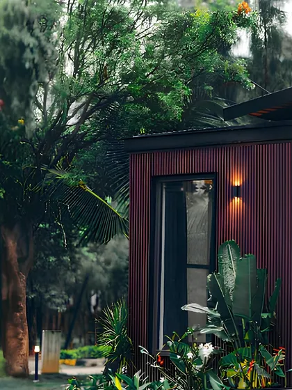 A close-up of a home with deep red WPC cladding, surrounded by lush greenery. This image captures the essence of efficient luxury, where high-end materials meet natural beauty.