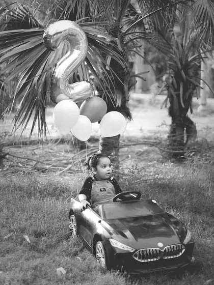 A classic black and white shot of a toddler in a toy car, part of our outdoor car-themed birthday shoot.