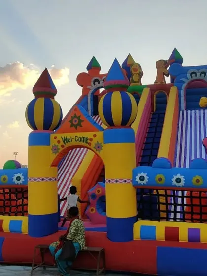 A large fun city style bouncy with multiple slides and clown decorations, photographed at dusk.