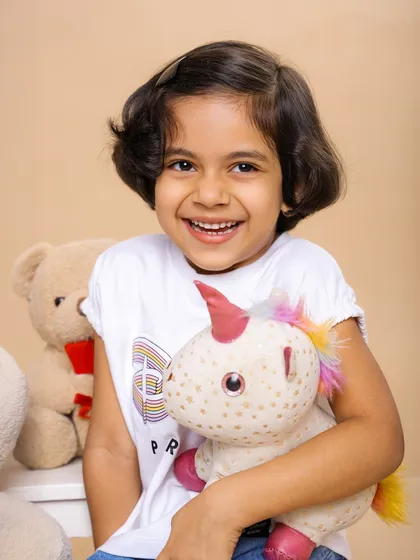 A bright and happy smile from this little girl as she hugs her unicorn toy. We love capturing the special bond children have with their favorite toys.