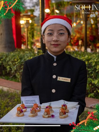 A server in a Santa hat offers a tray of smoked salmon canapés at a Christmas event. Our team embraces the festive spirit while delivering impeccable service.