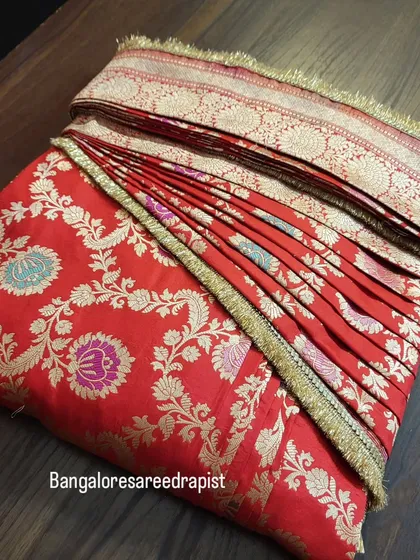 A classic red bridal Banarasi saree, pre-pleated and box-folded for a bride. I take special care with heavy bridal sarees to ensure the pleats are secure and the rich fabric is handled correctly, so the bride feels confident on her big day.