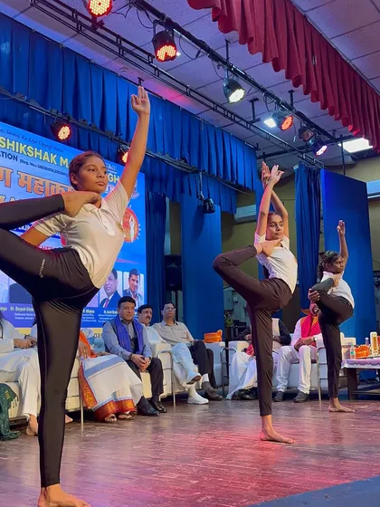 Grace and balance on display with the standing head-to-knee pose, part of a choreographed routine for an auditorium event.