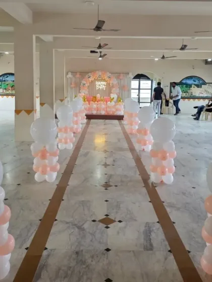 Balloon pillar decorations lining an entryway for a party in a community hall.