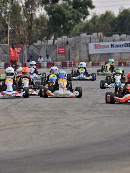 A pack of Mini Max karts navigates the track during a race, showcasing the intense competition.