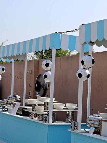 Themed food stalls for the football party, designed with blue and white striped awnings and decorated with soccer balls.