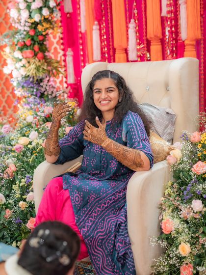 The sister of the bride at the Mehendi ceremony. She is wearing a comfortable yet chic printed blue and pink kurta set, perfect for getting her henna done while still looking festive.