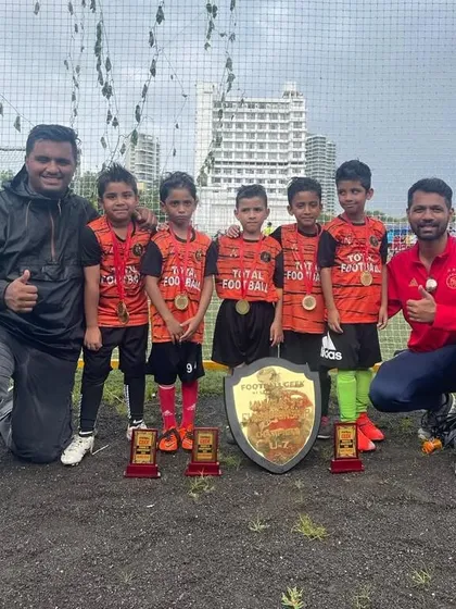 Our U7 champions of the Mumbai 7s Championship Cup, posing with their coaches and trophies.