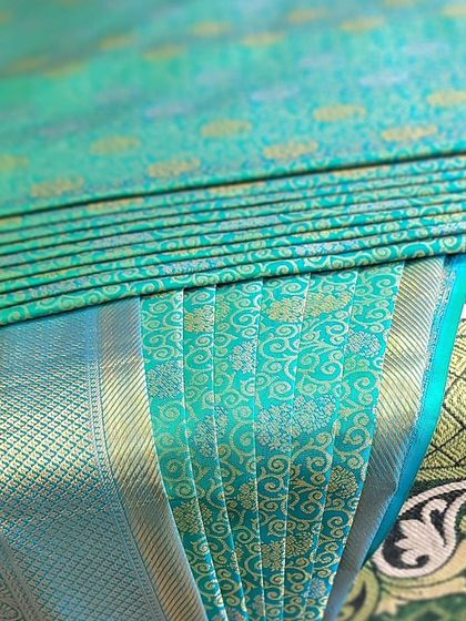 A close-up of the pleats on a turquoise bridal saree for a reception.