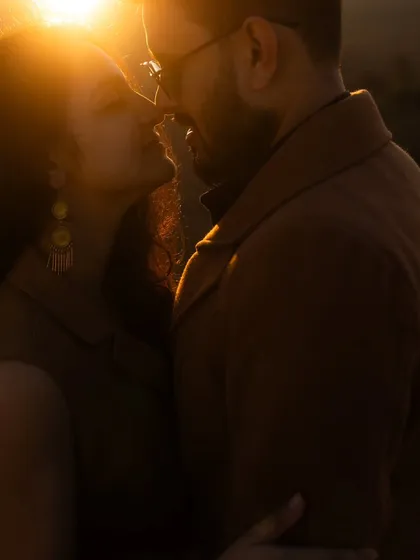 A beautifully backlit close-up of the couple, with the setting sun creating a warm, golden halo around them. A perfect golden hour portrait.