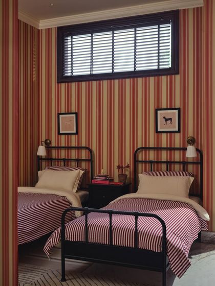 A frontal view of the twin beds in the guest room. The symmetry, high ceilings, and pattern-on-pattern design give this compact room a sense of old-world charm and deliberate composition.