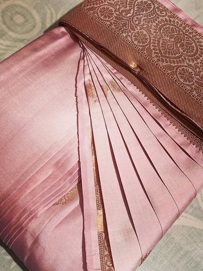 A soft pink silk saree with a bronze border. The pleats are set, making it ready to drape in just a few minutes.