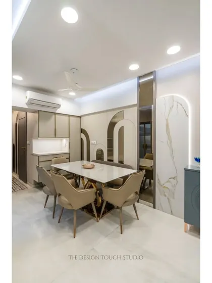 A full view of a dining area where modern design meets artistic flair. The space is characterized by arched wall motifs, a marble-top table with a sculptural base, and comfortable upholstered chairs.