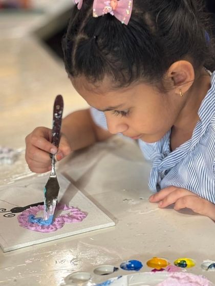 A young artist completely focused on her butterfly texture painting. Our workshops are for all ages, providing a space for kids to explore their creativity with palette knives and thick paints.