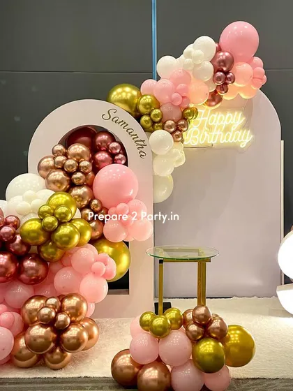 A premium birthday backdrop with a unique double-arch design. A cascade of pink, white, and metallic balloons flows through the arches, creating a modern and dynamic photo wall.