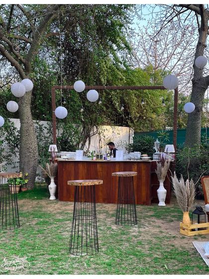 This outdoor event featured a full-service wooden bar set under a simple frame, allowing the natural beauty of the garden to shine. White paper lanterns and pampas grass arrangements tied the look together.