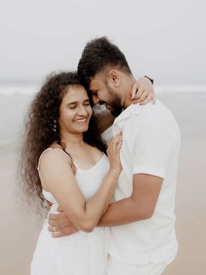 A sweet and tender moment between a couple on the beach, their smiles and embrace showing their deep connection.