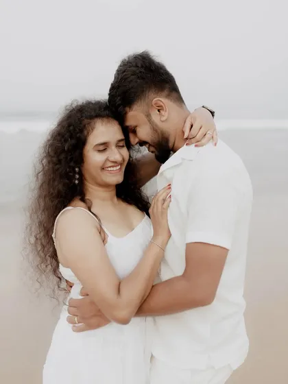 A sweet and tender moment between a couple on the beach, their smiles and embrace showing their deep connection.