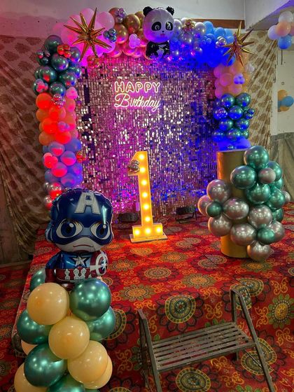 A close-up of the mixed-theme first birthday backdrop, featuring a Captain America balloon and a light-up number '1'.