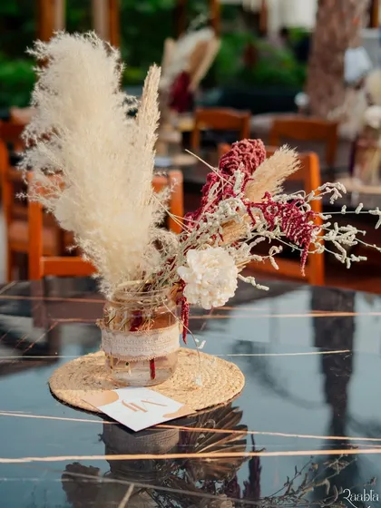 A centerpiece detail, featuring dried flowers and pampas grass in a rustic jar, perfect for the boho theme.