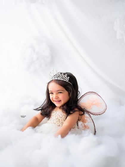 A joyful, laughing angel sitting amongst the clouds. Her happiness is radiant.