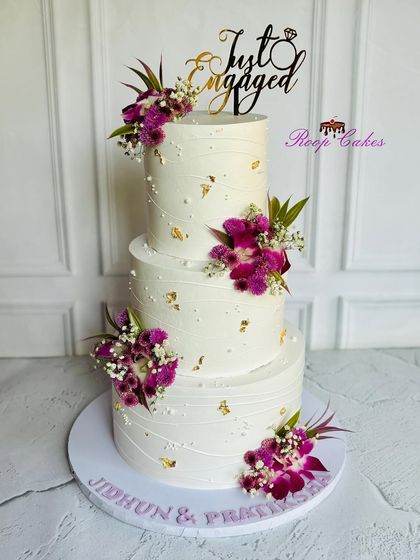 Elegantly crafted for a perfect beginning. This stunning three-tier 'Just Engaged' cake is adorned with fresh purple orchids and delicate gold leaf for a touch of luxury.