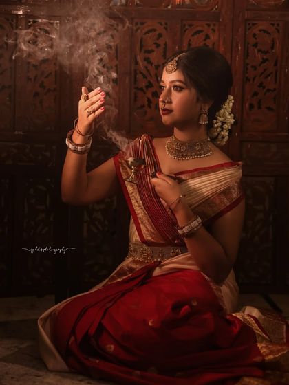 Portraits from a makeup shoot, showcasing a model in a classic red and cream saree. The images highlight the flawless makeup and traditional styling in a beautiful garden setting.