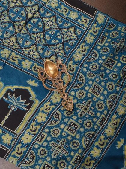 A close-up of a beautiful blue and green Ajrakh block-printed fabric. The intricate details and natural dyes are a testament to this ancient craft.