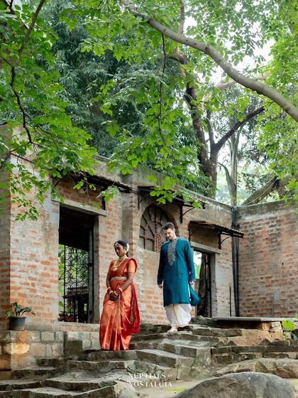 A cross-cultural couple walks down the stone steps of a rustic, unfinished structure, creating a beautifully textured and atmospheric shot.