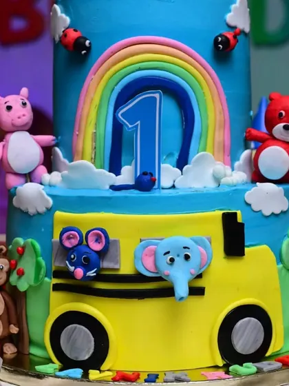A close-up of a vibrant Cocomelon-themed birthday cake, showcasing the detailed character toppers and colorful design.