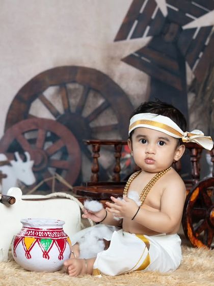 A cute baby boy sitting in a village setting, playing with a pot of butter.