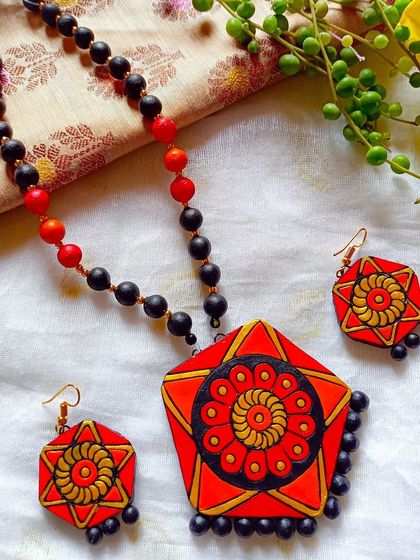 The same hexagonal pendant necklace, here in a bold red, orange, and yellow color scheme. The geometric shape combined with the floral motif creates a lovely modern-ethnic fusion.
