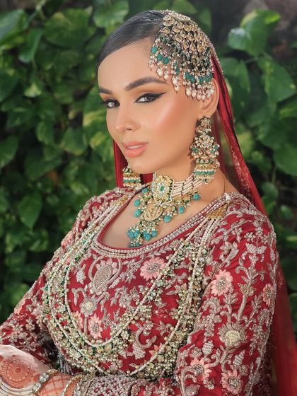A close-up of a Nikkah bride with a bold winged liner and stunning emerald jewellery. The makeup is glamorous yet graceful, with a focus on flawless skin and captivating eyes.