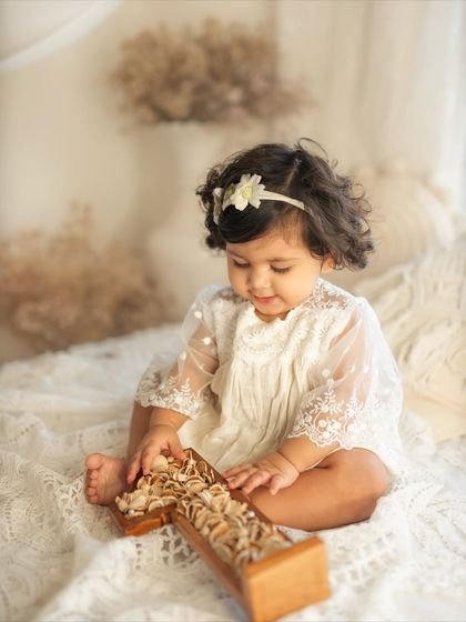 The birthday girl is fascinated by the shell-filled "One" prop in this close-up shot from her natural and airy first birthday session.