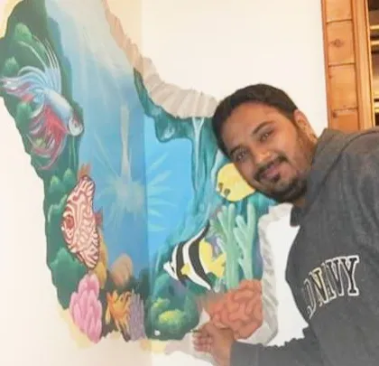 Here I am with a 3D-effect underwater mural that looks like the wall is broken away to reveal a coral reef. This technique is a great way to add depth and a surprising element to a room, making the art feel interactive and alive.
